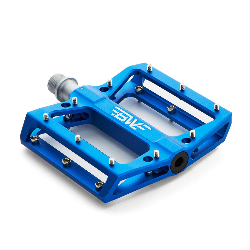 Large platform mountain bike pedal with replaceable traction pins. Dark blue mountain bike pedal viewed from the corner on a white background.