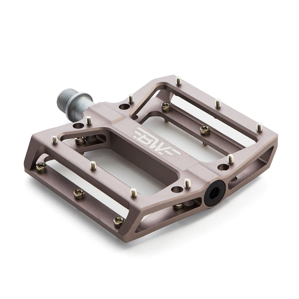 Large platform mountain bike pedal with replaceable traction pins. Titanium color aluminum mountain bike pedal viewed from the corner with a white background.
