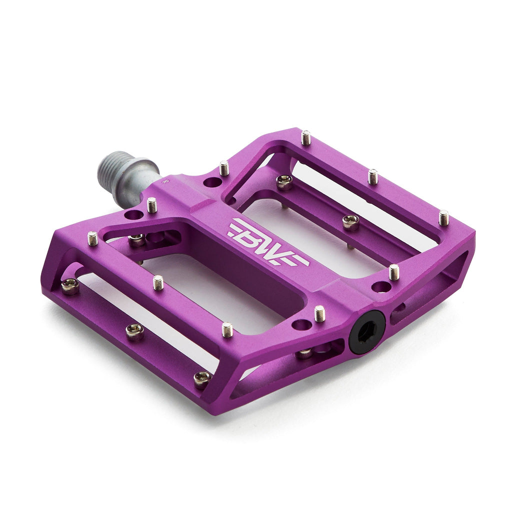 Large platform mountain bike pedal with replaceable traction pins. Purple mountain bike pedal viewed from the corner on a white background.