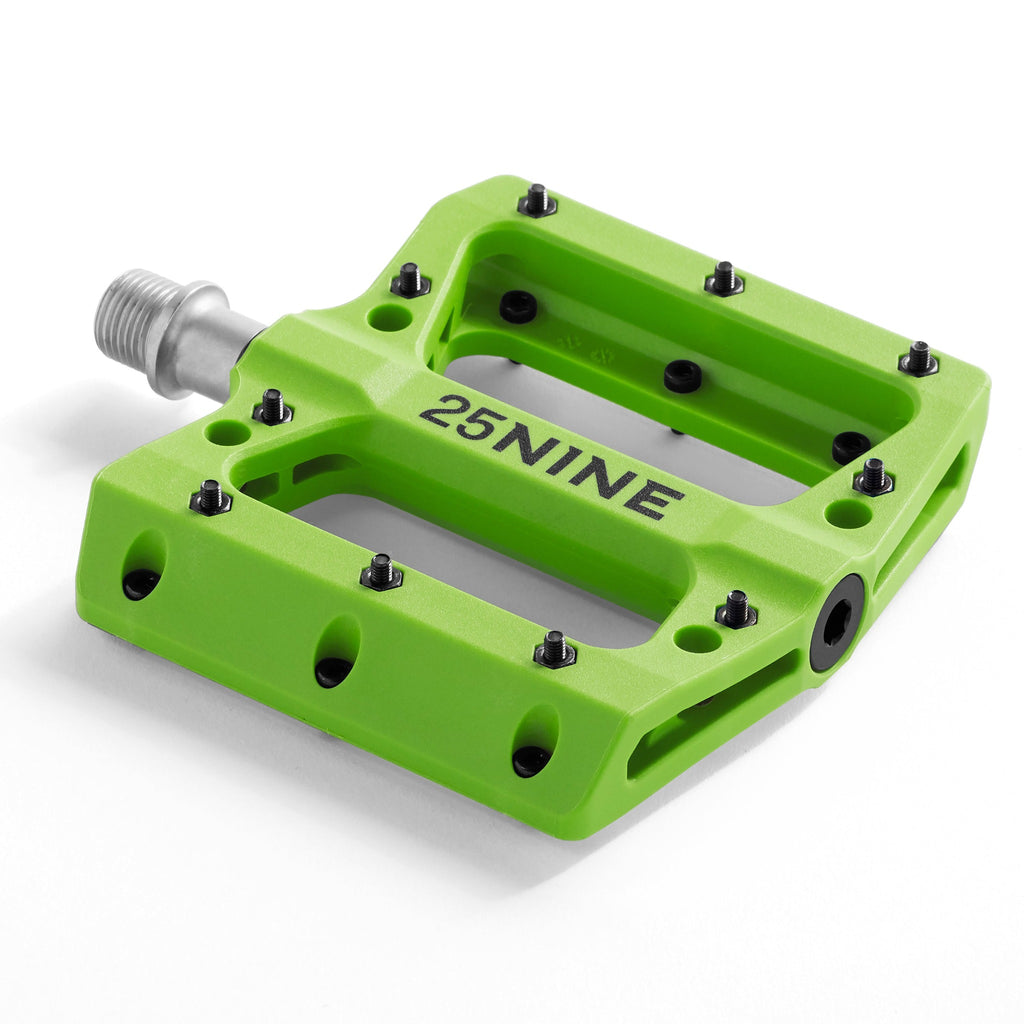 High traction bike pedal with removable pins. Green bike pedal from a corner view on a white background.