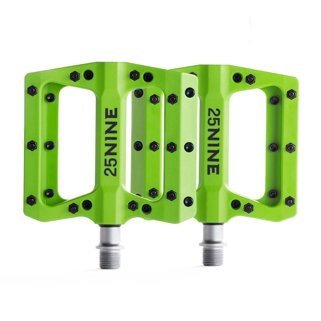 High traction bike pedals with removable pins. Green bike pedals from a corner view on a white background.