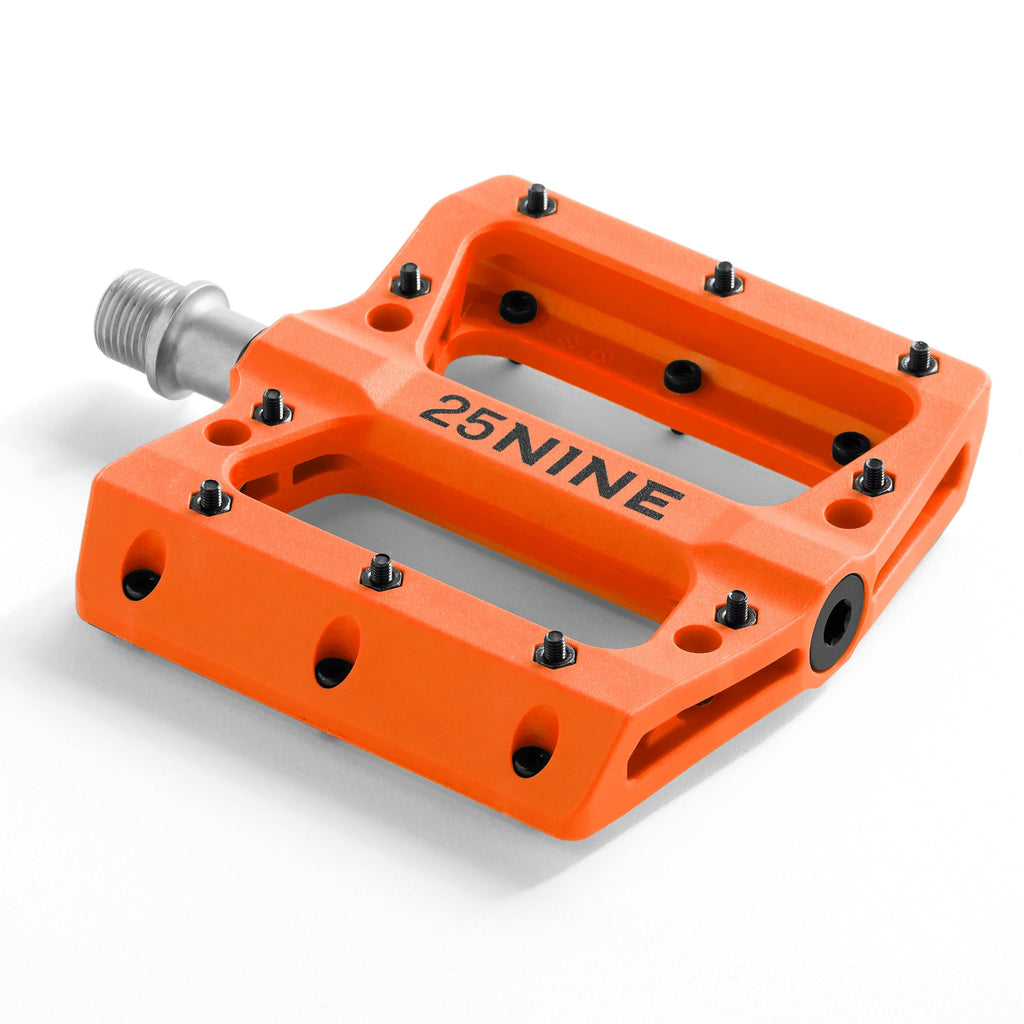 High traction bike pedal with removable pins. Orange bike pedal from a corner view on a white background.