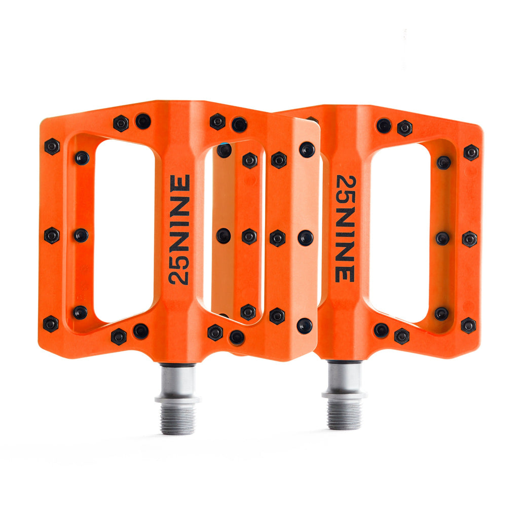 High traction bike pedals with removable pins. Orange bike pedals from a corner view on a white background.