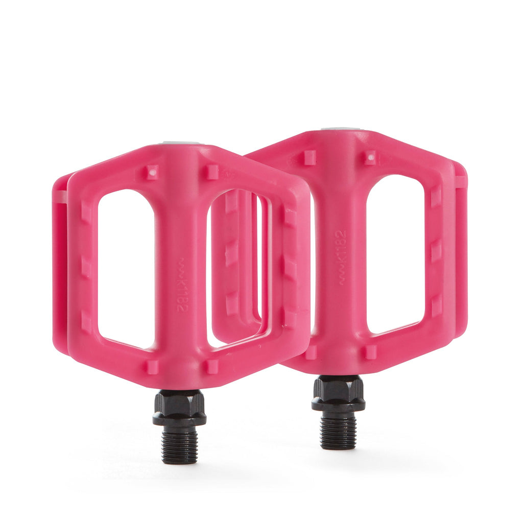 bright pink bicycle pedals for youth upright with white background