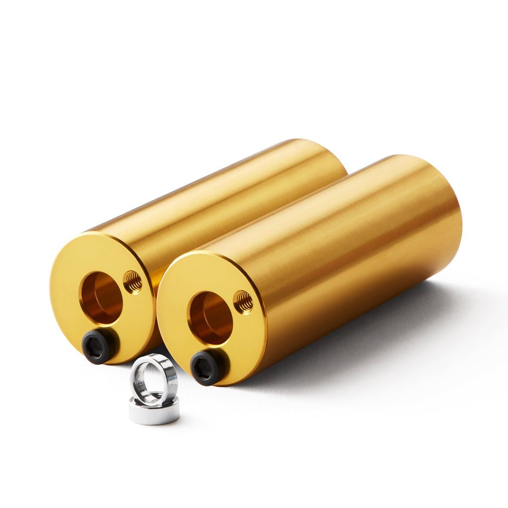 Set of gold bmx pegs with white background.