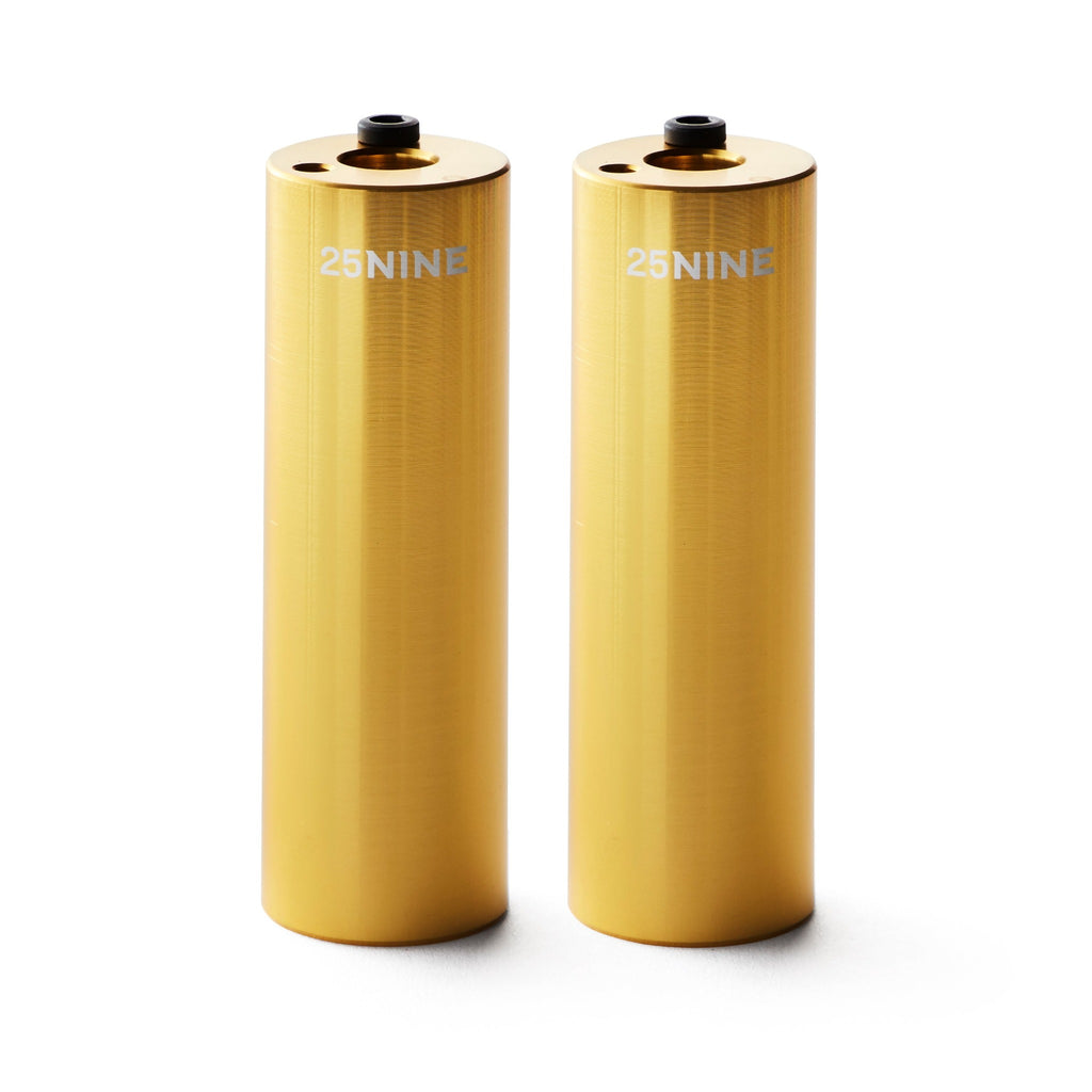 Set of gold bmx pegs with white background.