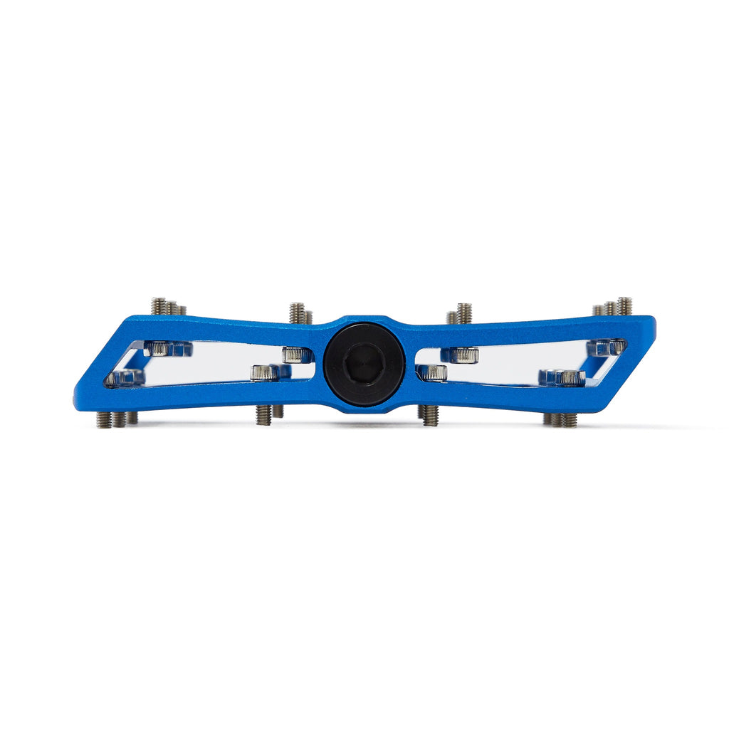 Large platform mountain bike pedal with replaceable traction pins. Dark blue mountain bike pedal viewed from the side on a white background.