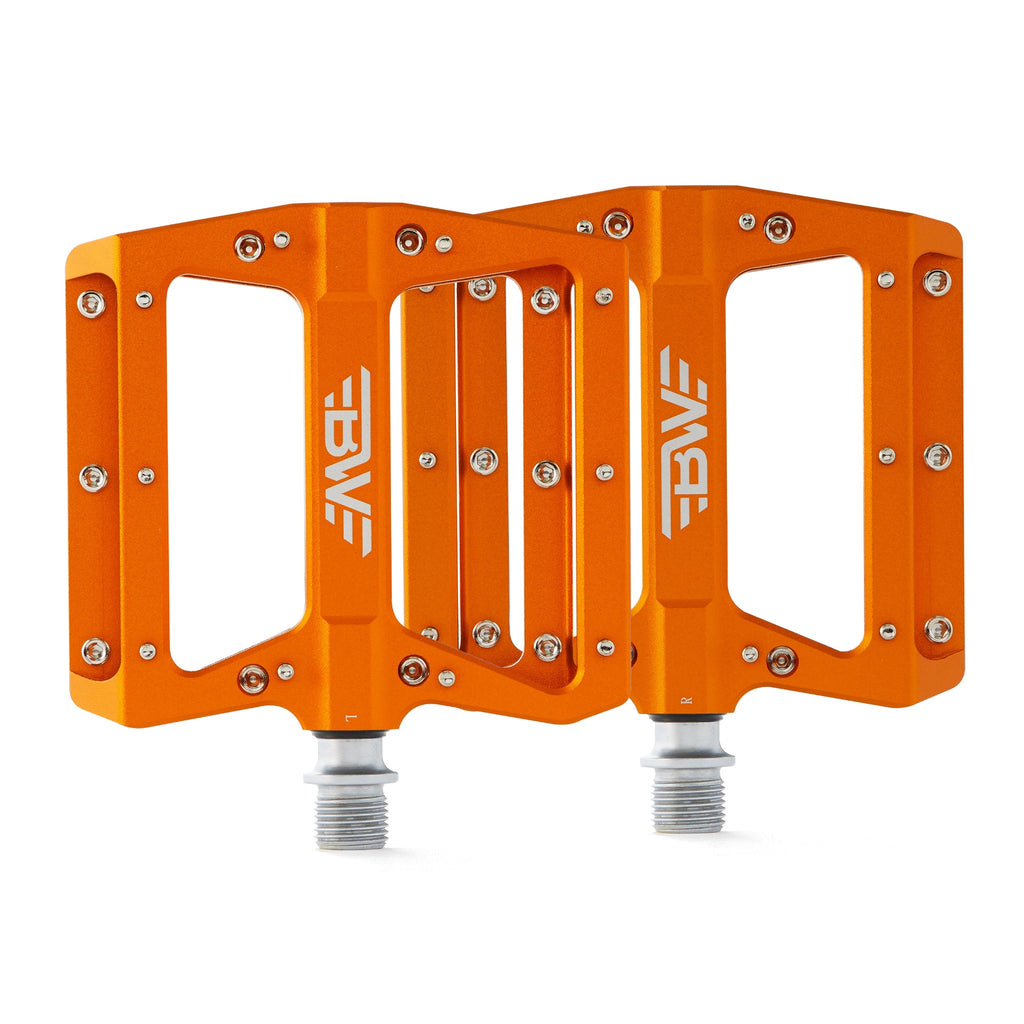 Large platform mountain bike pedals with replaceable traction pins. Orange bike pedals viewed from the top on a white background.