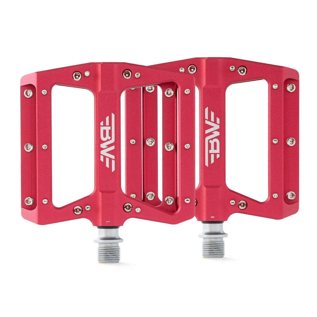 Large platform mountain bike pedals with replaceable traction pins. Red mountain bike pedals viewed from the top with a white background.