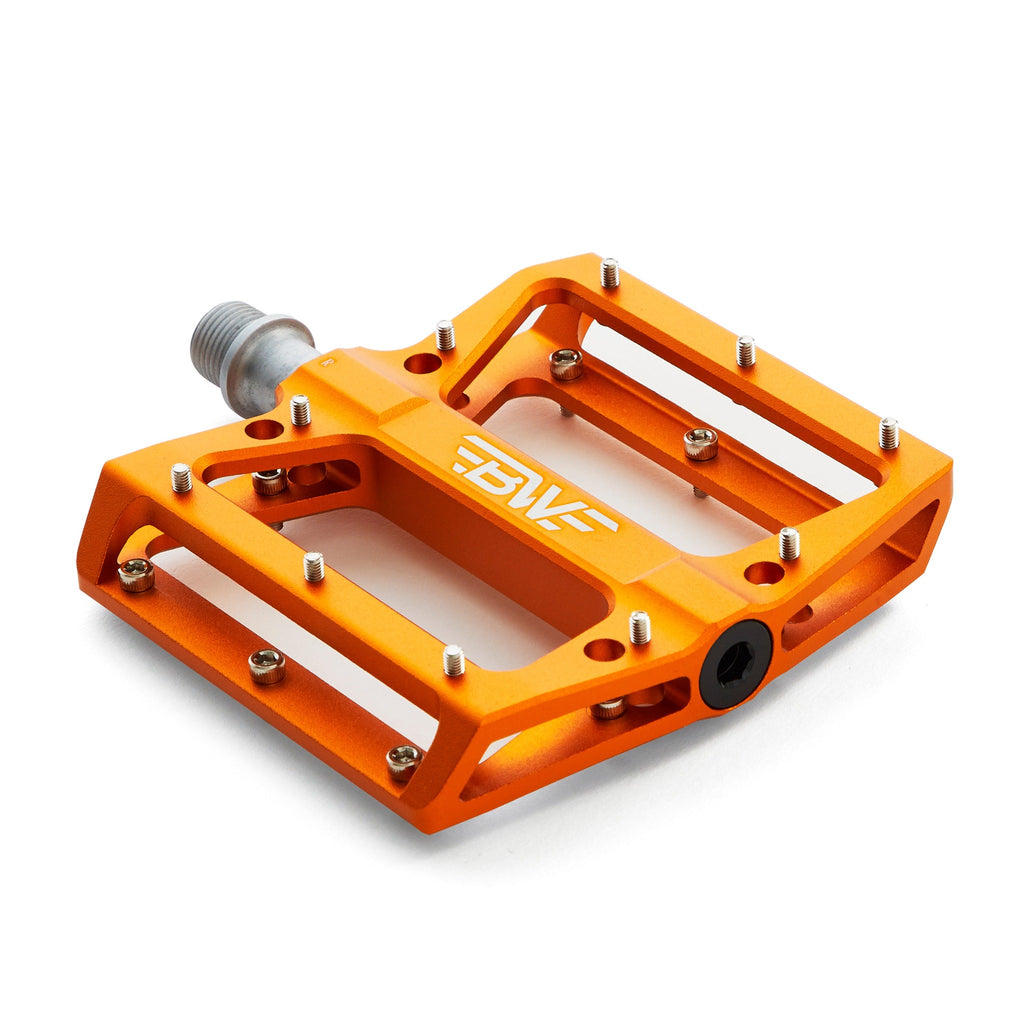 Large platform mountain bike pedal with replaceable traction pins. Orange bike pedal viewed from the corner on a white background.