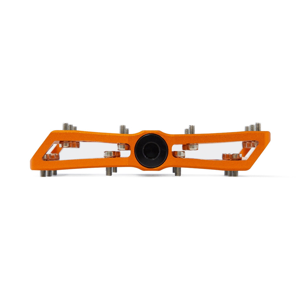 Large platform mountain bike pedal with replaceable traction pins. Orange bike pedal viewed from the side on a white background.
