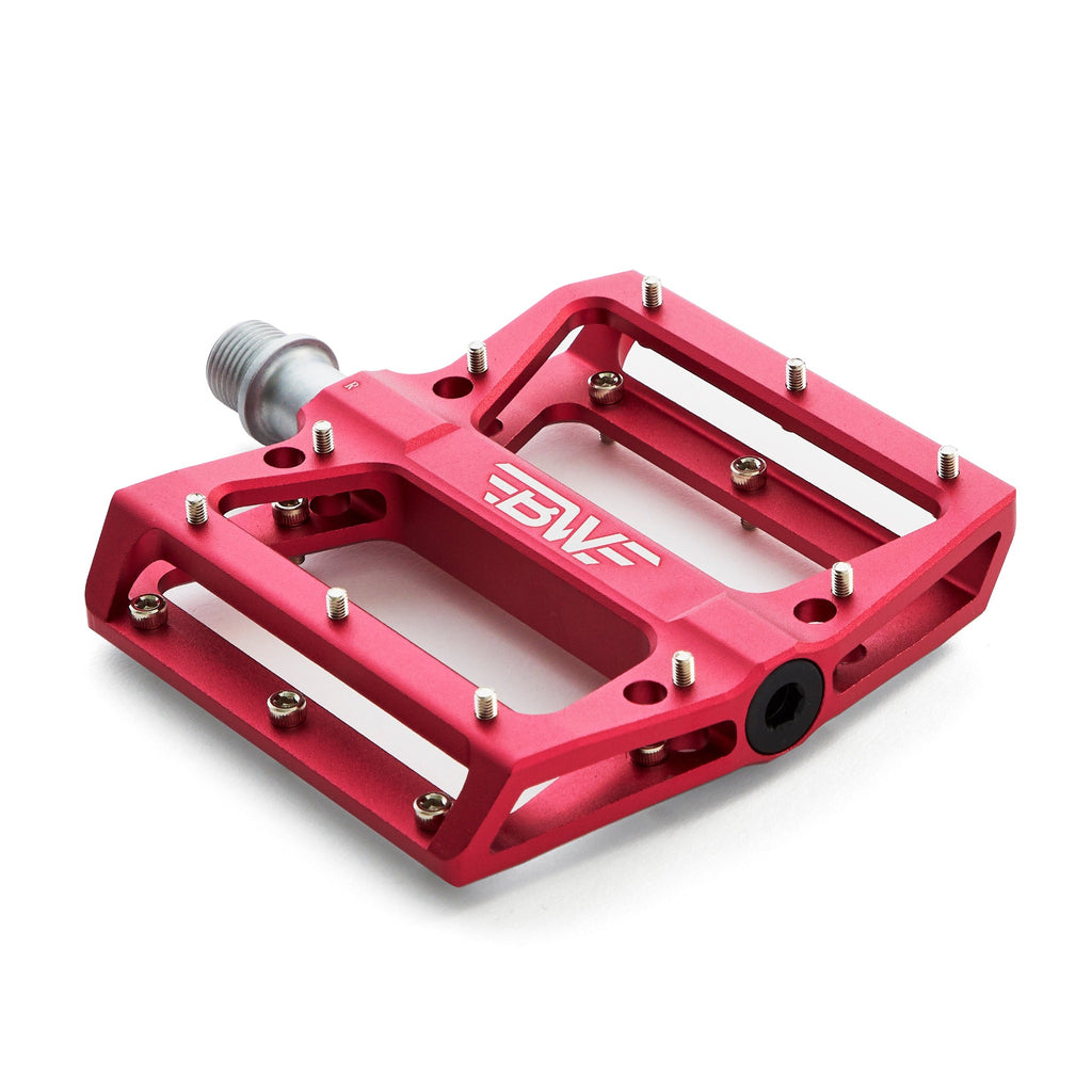 Large platform mountain bike pedal with replaceable traction pins. Red mountain bike pedal viewed from the corner with a white background.
