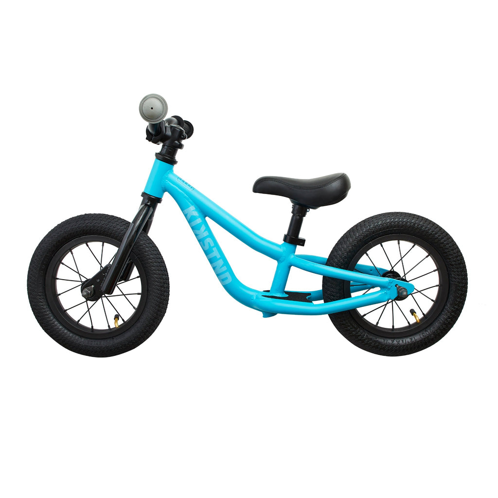 Light blue balance bike for kids. Side view on white background.