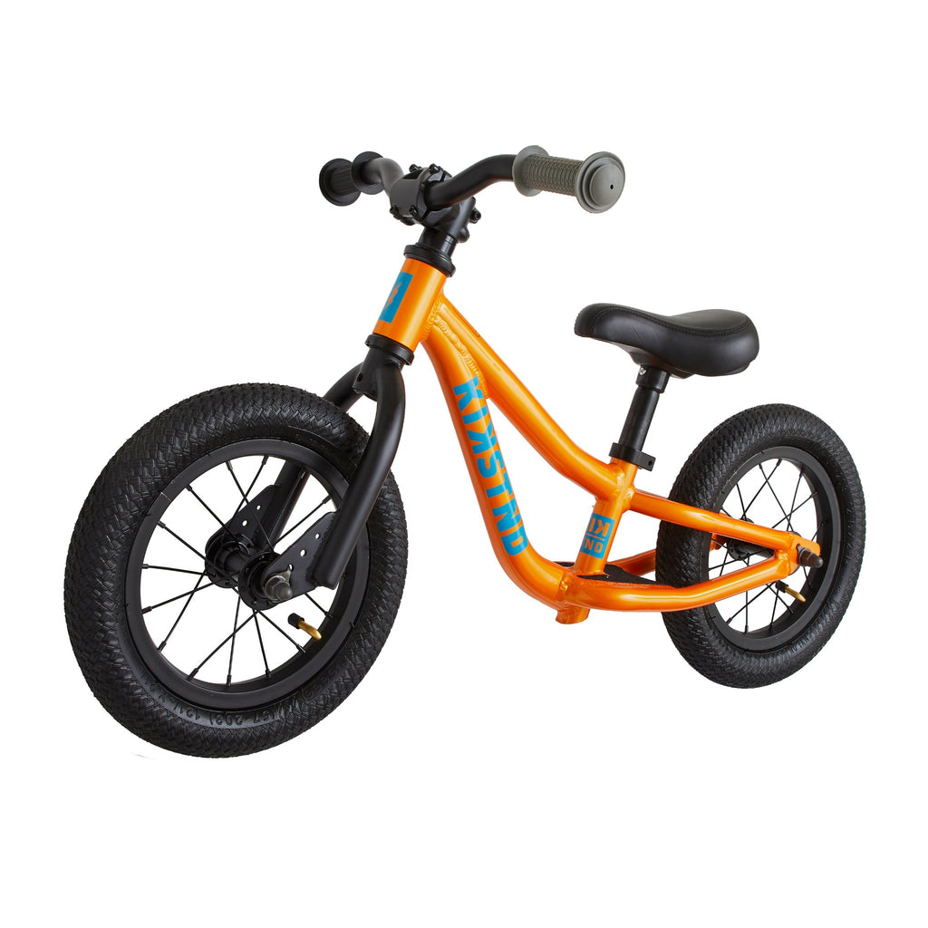 Orange balance bike for kids. White background.