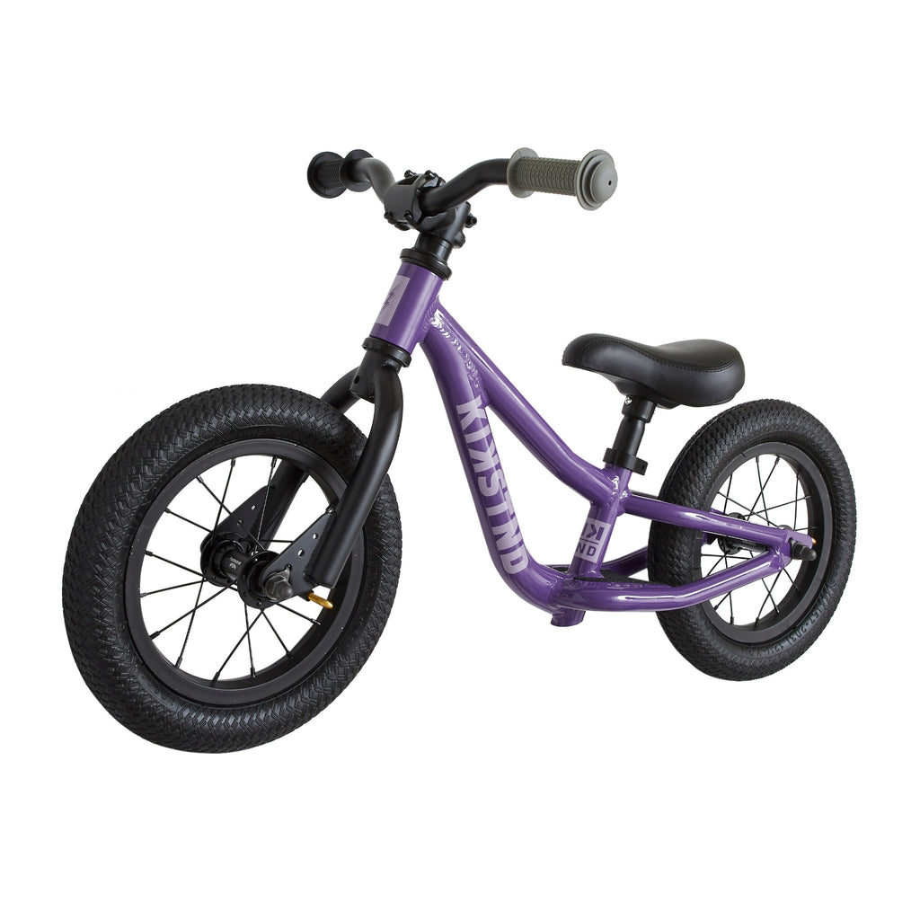 Purple balance bike for kids. White background.